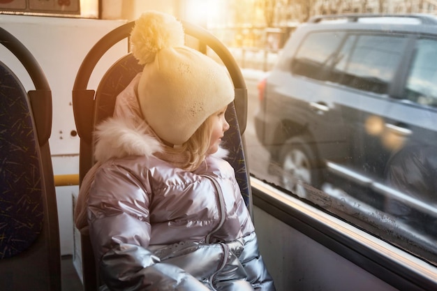 Niña en autobús viendo en la ventana del transporte público de la ciudad