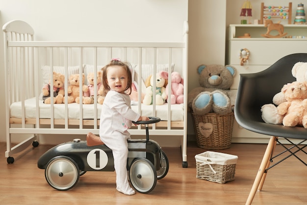 niña en un automóvil retro en la habitación de los niños