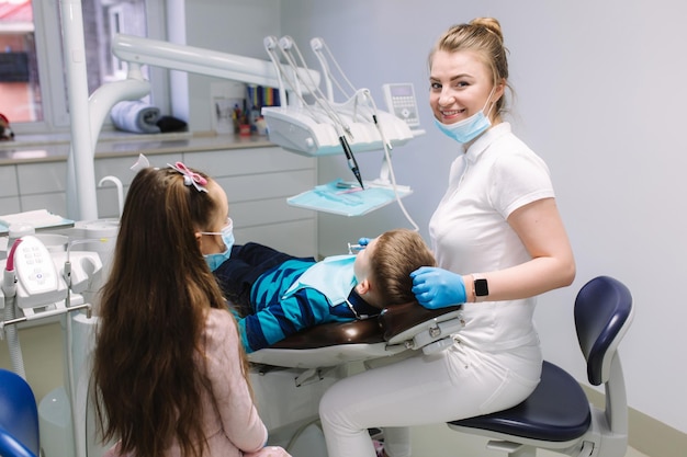 La niña ayuda a la dentista a examinar los dientes nuevos y al tratamiento de las caries