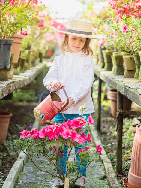 Niña ayuda a regar plantas y jardinería en invernadero.