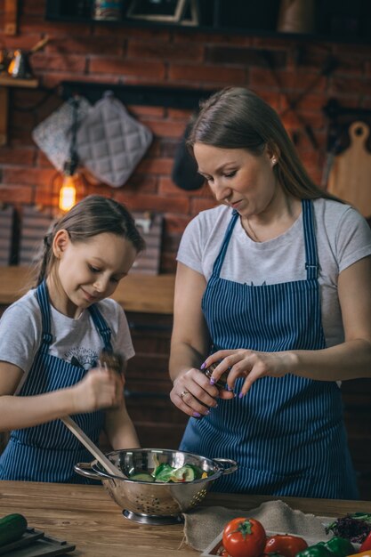 Niña ayudando a la madre con condimento de ensalada