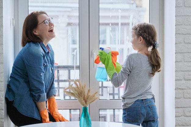 Niña ayudando a la mujer a lavar las ventanas, hacer limpieza en casa