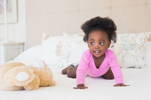 Niña en babygro rosado que se arrastra en cama