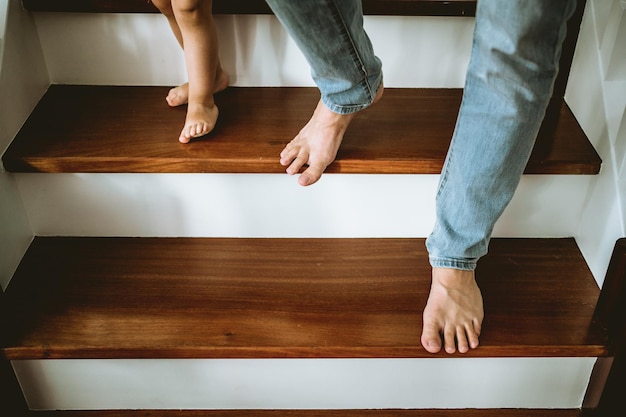 Foto una niña bajando las escaleras de la mano de su padre.