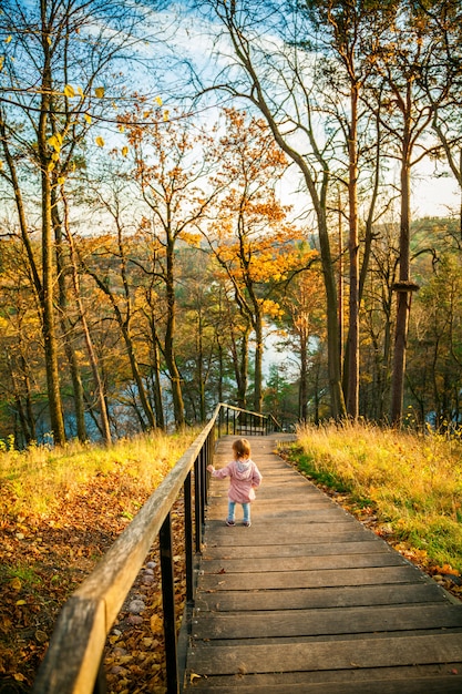 Niña bajando las escaleras en el parque de otoño