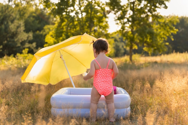 Niña se baña en una piscina inflable.