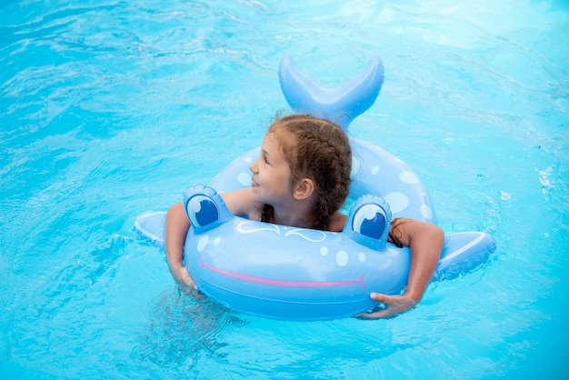 Una niña se baña en la piscina. El verano. Vacaciones.