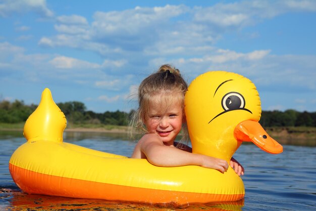 Niña se baña en el río en pato inflable