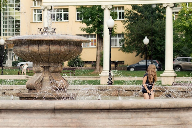 Una niña bañándose en una fuente de la ciudad