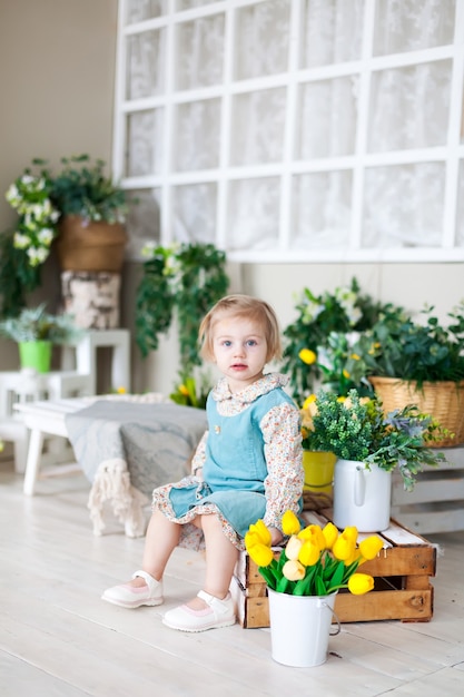 Niña en banco de madera con flores de primavera.