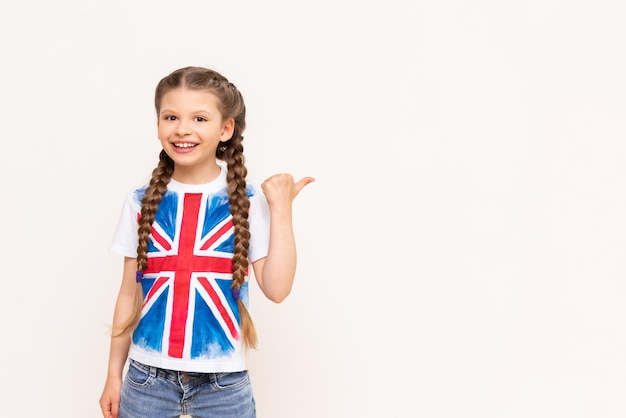 Una niña con la bandera de Gran Bretaña señala su anuncio en un fondo blanco aislado