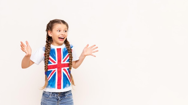 Una niña con la bandera de Gran Bretaña señala su anuncio en un fondo blanco aislado