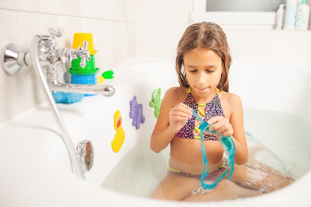 Una niña en el baño usa gafas de natación.