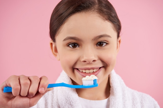 Niña en bata de baño es cepillarse los dientes