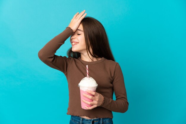 Niña con batido de fresa aislado sobre fondo azul se ha dado cuenta de algo y tiene la intención de la solución