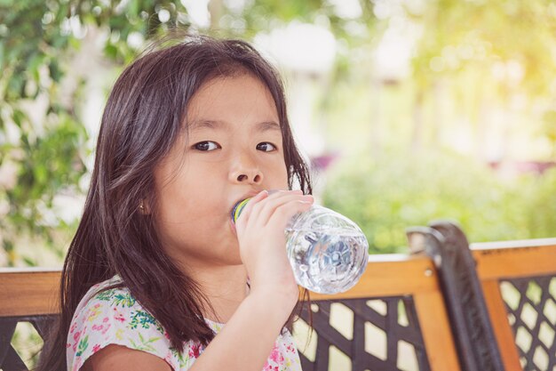 Niña bebe agua de una botella