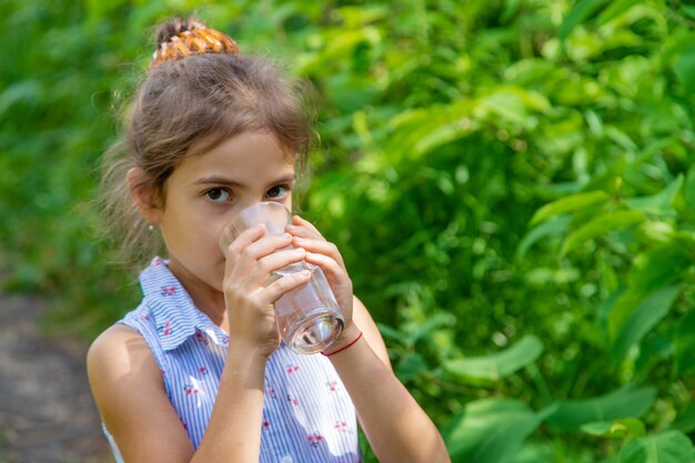 Niña bebe agua de un vaso. Enfoque selectivo. Niño.