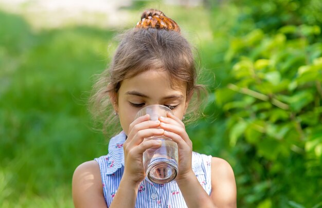 Niña bebe agua de un vaso. Enfoque selectivo. Niño.