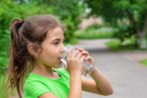 Niña bebe agua de un vaso. Enfoque selectivo. Niño.