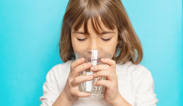 Niña bebe agua de un vaso Enfoque selectivo