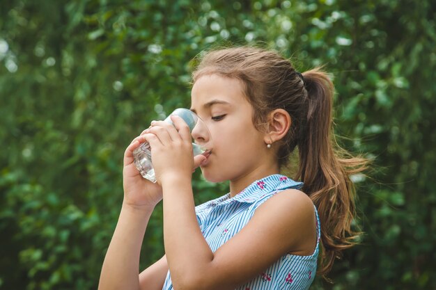 Niña bebe agua de un vaso.