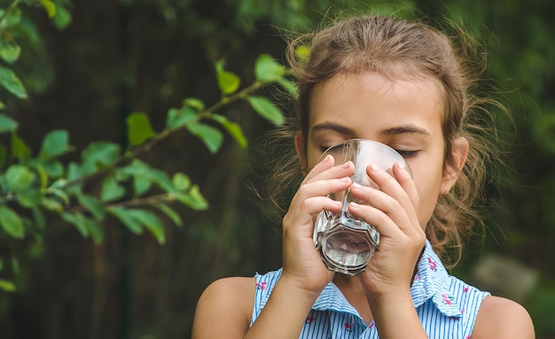 Niña bebe agua de un vaso.