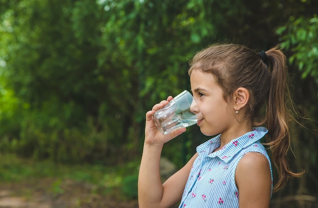 Niña bebe agua de un vaso.