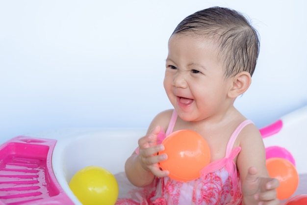 Foto niña bebé en el baño jugando a la pelota.