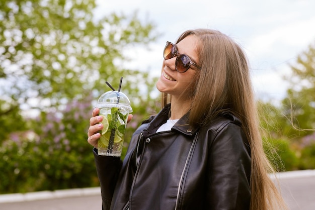 Niña bebe un refrescante cóctel con limón en la ciudad