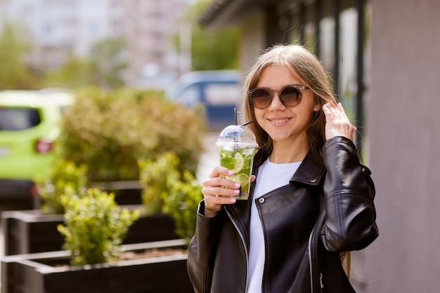 Niña bebe un refrescante cóctel con limón en la ciudad