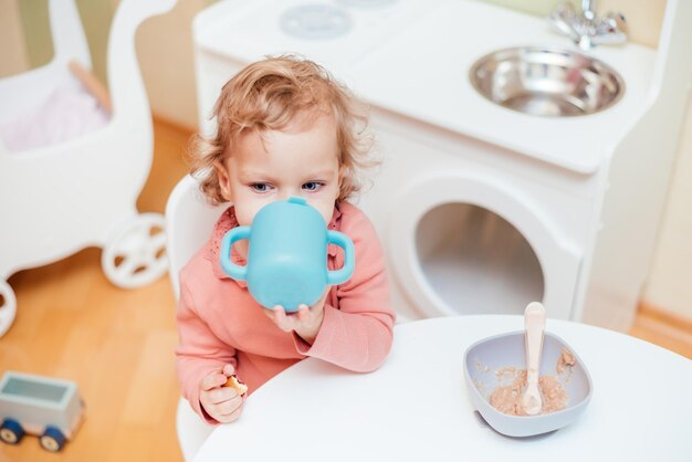 Niña bebiendo agua de un vaso de plástico