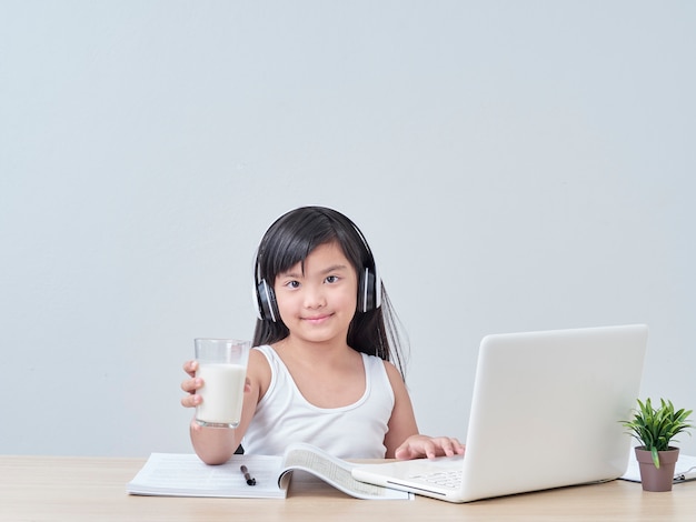 Niña bebiendo leche mientras estudiaba