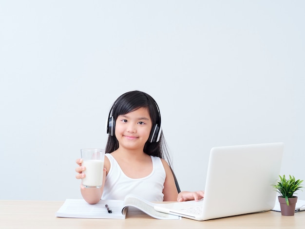 Niña bebiendo leche mientras estudiaba