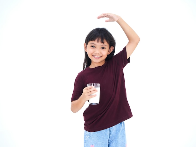 Niña bebiendo leche sobre fondo blanco.