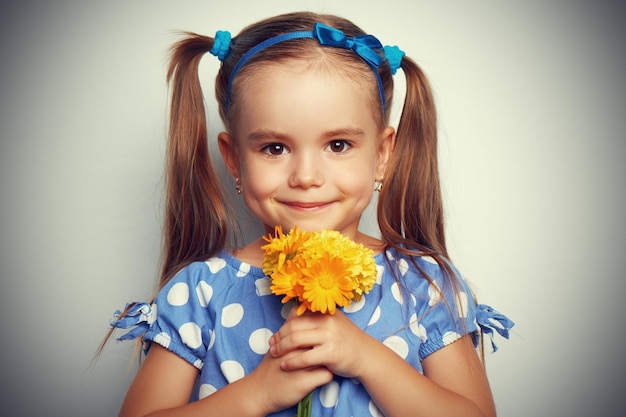 Niña de belleza con un ramo de flores amarillas.