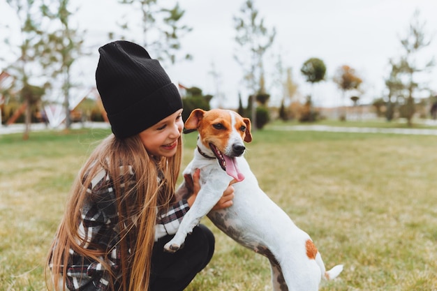 Una niña besa y abraza a su perro Jack Russell terrier en el parque Amor entre el dueño y el perro un niño sostiene a un perro en sus brazos