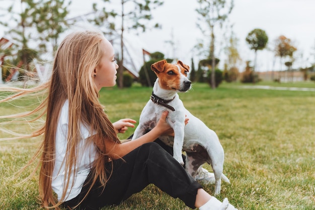 Una niña besa y abraza a su perro Jack Russell terrier en el parque Amor entre el dueño y el perro un niño sostiene a un perro en sus brazos