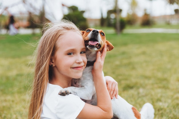 Una niña besa y abraza a su perro Jack Russell terrier en el parque Amor entre el dueño y el perro un niño sostiene a un perro en sus brazos