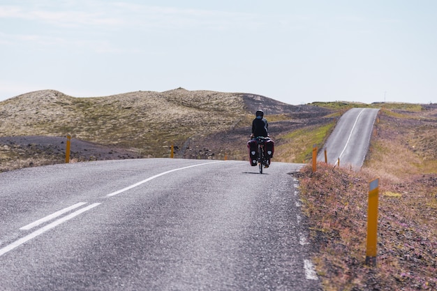 Foto niña en bicicleta por una carretera pavimentada en islandia.