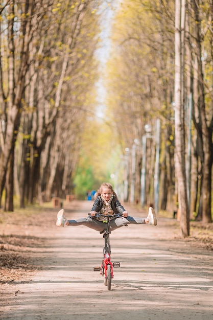 Niña en bicicleta en el hermoso día de otoño al aire libre en el parque