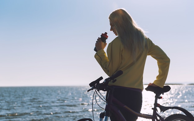 Una niña en bicicleta junto al mar.