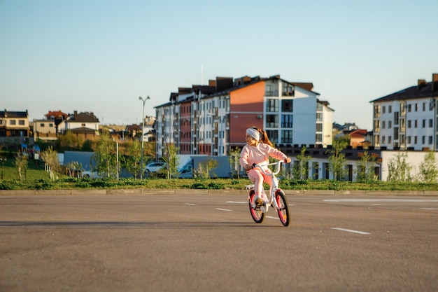 Niña en bicicleta en el parque de verano en bicicleta al aire libre