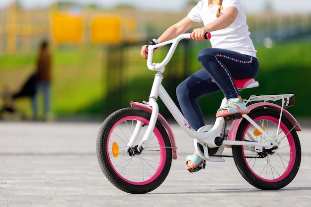 Niña en bicicleta en el parque de verano en bicicleta al aire libre