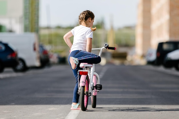 Niña en bicicleta en el parque de verano en bicicleta al aire libre