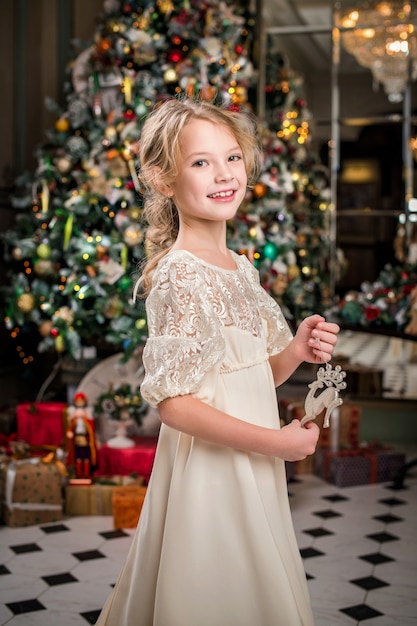 Niña bien vestida en casa bailando alrededor del árbol de Navidad