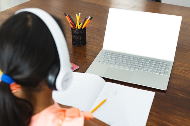 Niña biracial estudia en casa con espacio para copiar