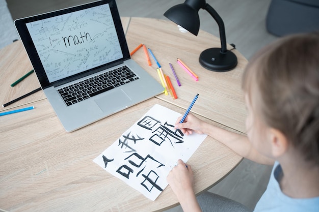 Una niña blanca en la lección de caligrafía china. niña aprendiendo chino