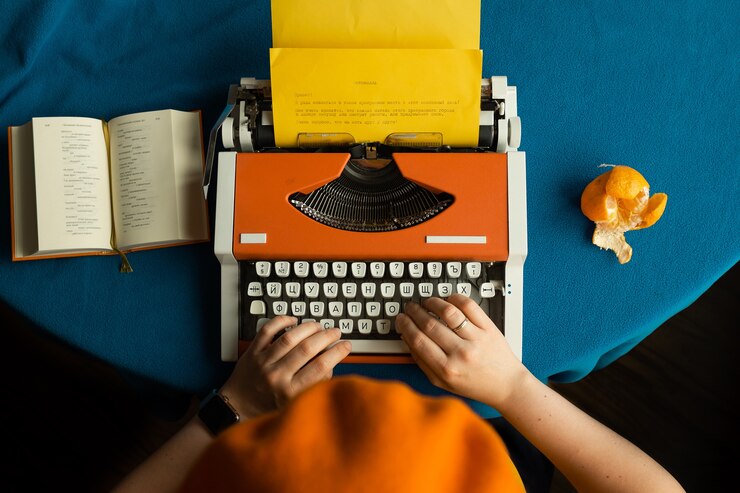 Foto una niña con una boina naranja está escribiendo en una máquina de escribir naranja, leyendo poesía y comiendo una mandarina