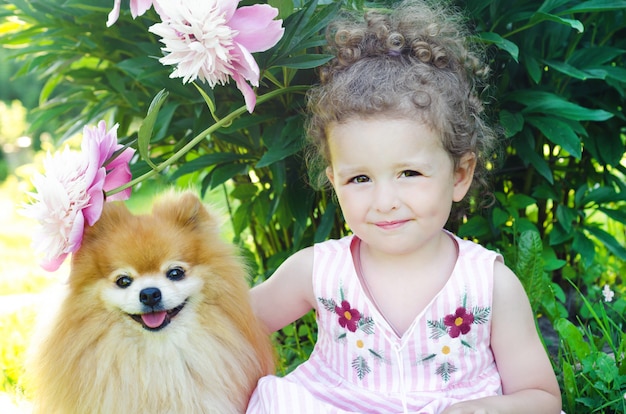 Foto niña bonita abrazando a su perro pomerania