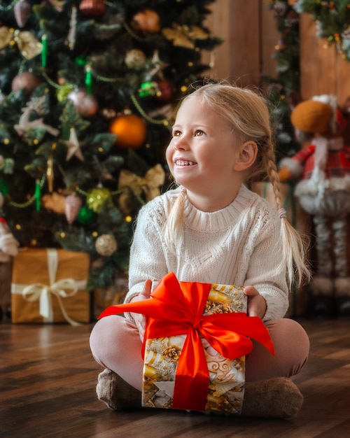 Niña bonita abre un regalo de navidad.